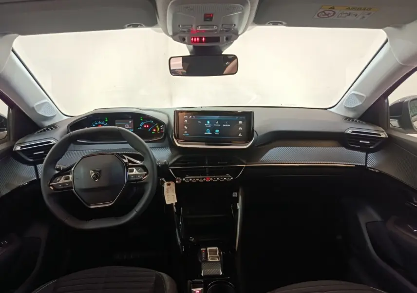 Vue intérieure frontale du tableau de bord et volant cuir de la Peugeot 208 électrique gris clair 2024.