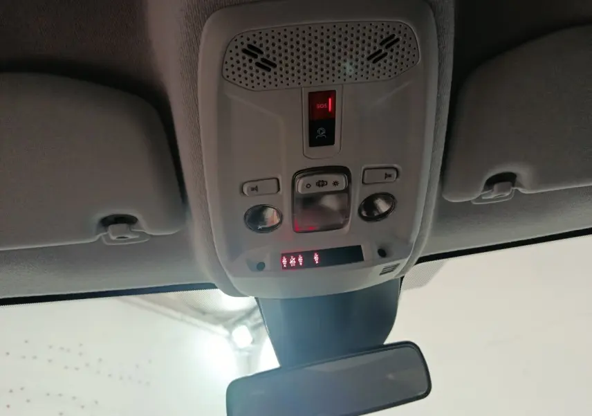 Vue intérieure du plafonnier gris clair avec commandes d’éclairage et bouton SOS allumé sur Peugeot 208 électrique 2024.