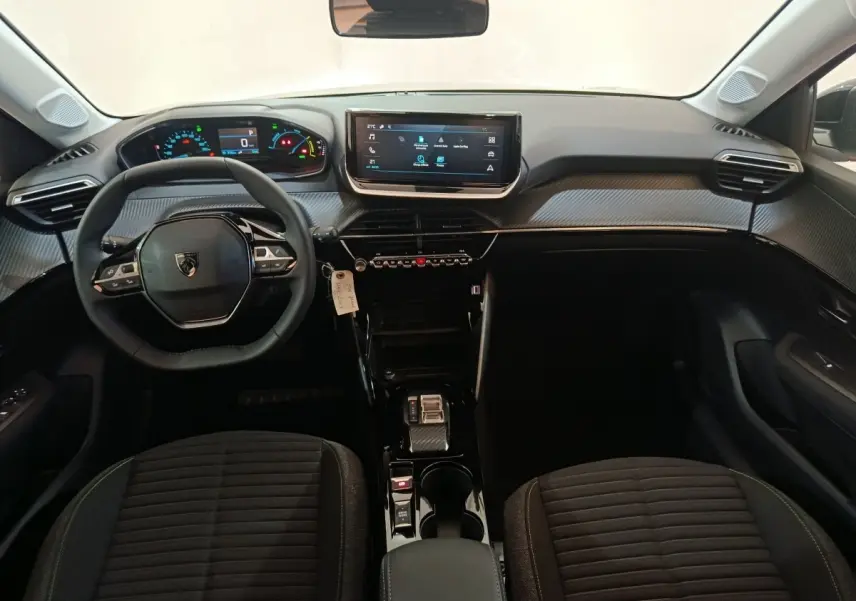Vue intérieure avant de la Peugeot 208 électrique 2024, volant cuir multifonctions et écran tactile central noir.
