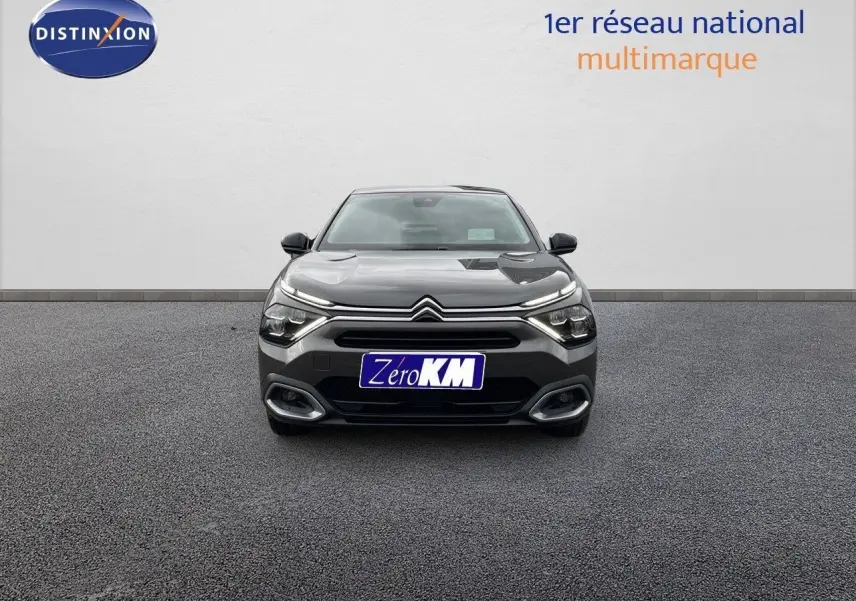 Vue avant d'une Citroën C4 2024 gris platinium métal avec ses phares LED allumés sur fond neutre.