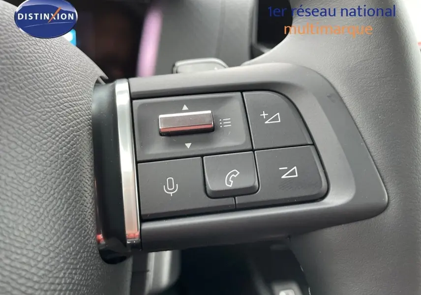 Gros plan sur les commandes au volant du côté gauche du Citroën C4 gris platinium 2024, boutons de volume et appel.