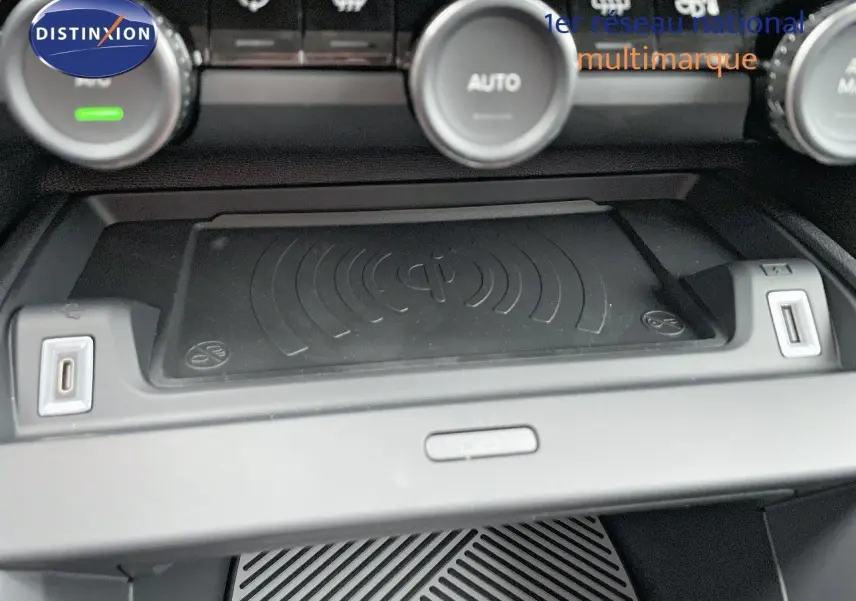 Gros plan sur la console centrale de la Citroën C4 2024 avec zone de recharge sans fil et commandes de climatisation.