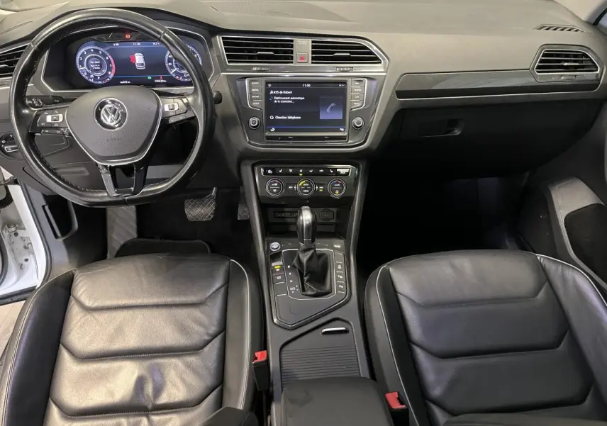 Vue intérieure frontale du Volkswagen Tiguan 2017 avec sièges cuir noirs, tableau de bord et console centrale équipée.