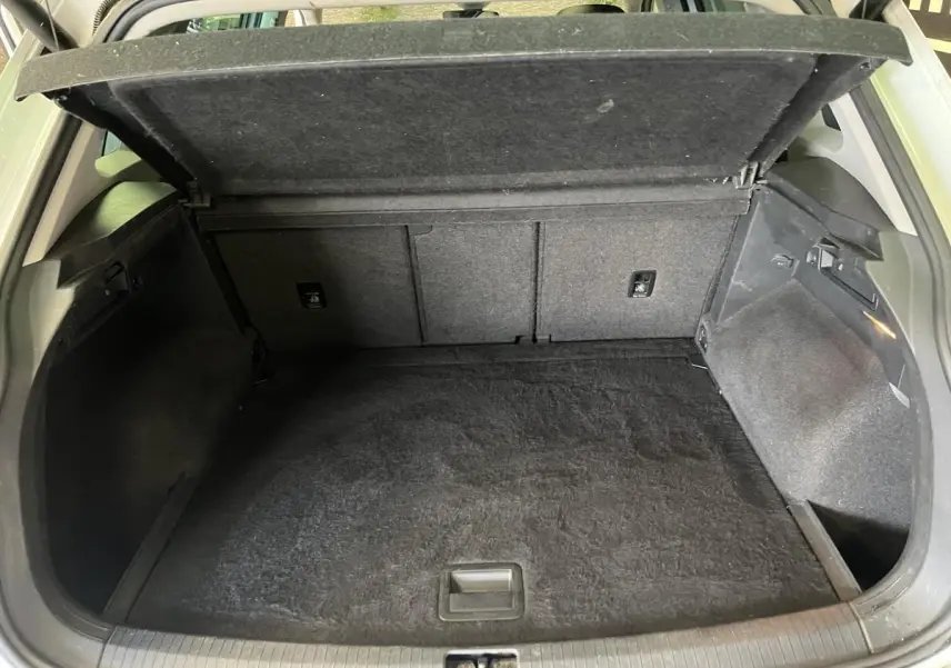 Coffre ouvert du Volkswagen Tiguan blanc vu de l'arrière, montrant un espace de chargement propre et vide.