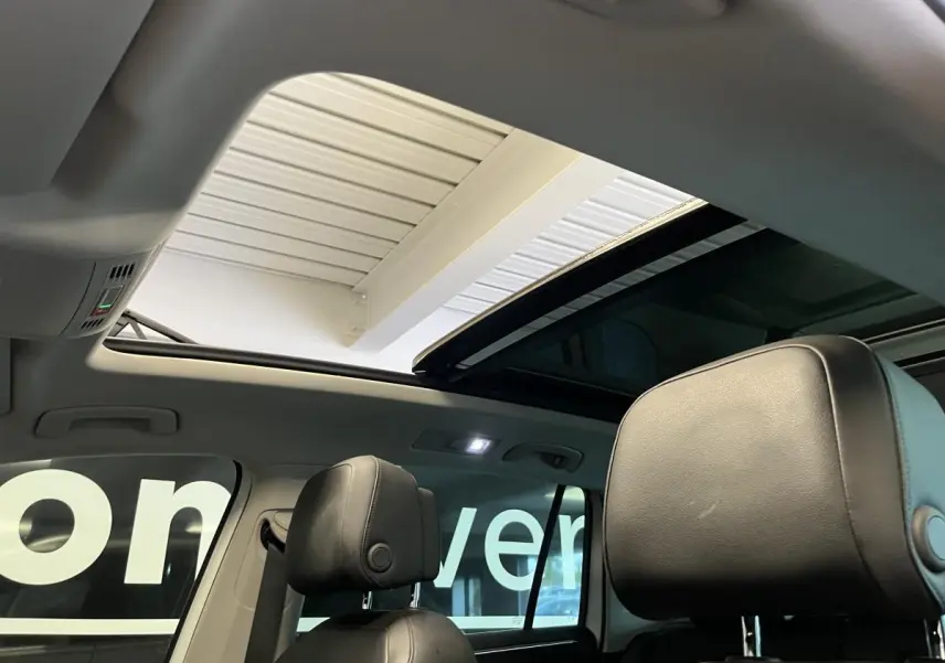 Vue intérieure du Volkswagen Tiguan 2017 montrant les appuis-tête avant en cuir noir et le toit ouvrant panoramique.