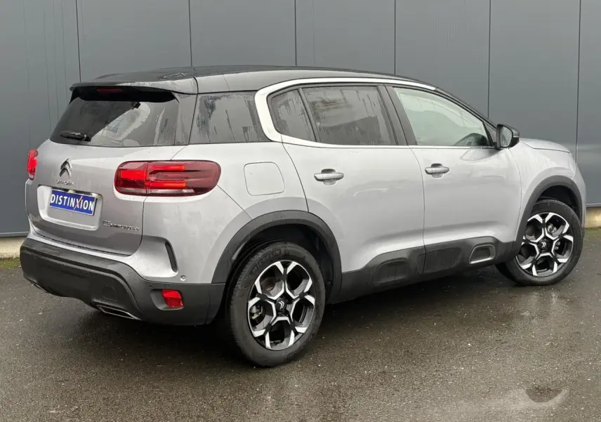Vue 3/4 arrière droite d'un Citroën C5 Aircross Hybrid gris Artense avec toit noir et jantes alliage 18 pouces.