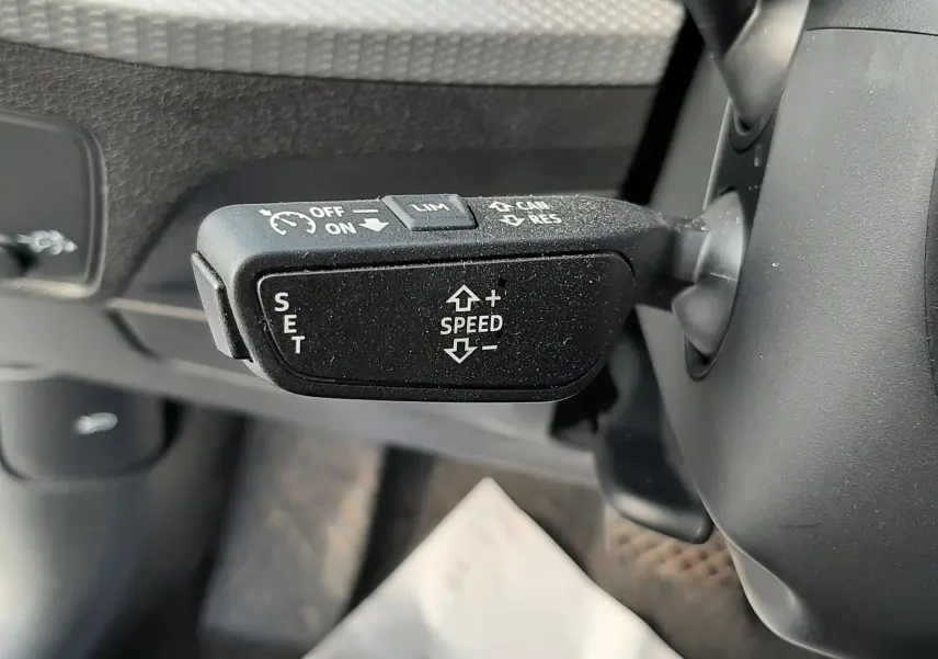 Gros plan sur le levier de régulateur de vitesse noir à gauche du volant de l'Audi Q2 35 TFSI 2023 noir mito metal.