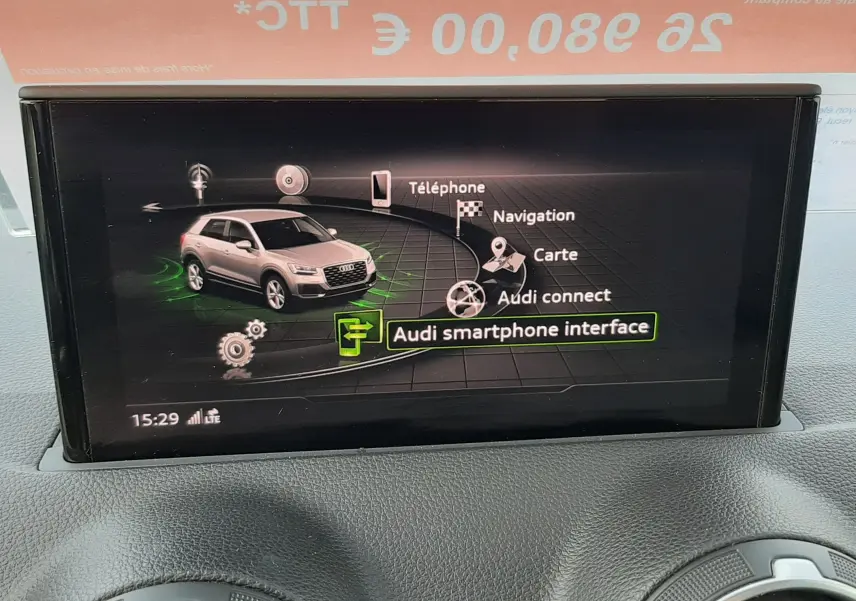 Écran central montrant l'interface multimédia avec une Audi Q2 argent en vue 3/4 avant sur fond noir.