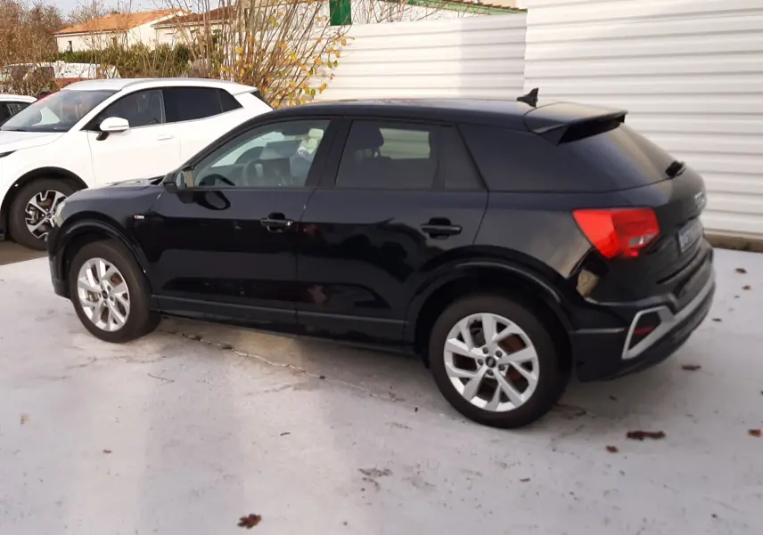 Audi Q2 noir mito metal vue de profil côté gauche, mettant en valeur ses lignes compactes et ses jantes argentées.