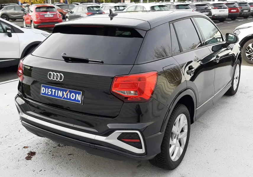 Audi Q2 35 TFSI S-Line noir mito metal vu en 3/4 arrière droit, avec feux arrière rouges et jantes argentées.