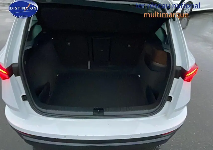 Coffre ouvert vu de l'arrière d'un Skoda Karoq blanc glacial avec feux arrière LED allumés.