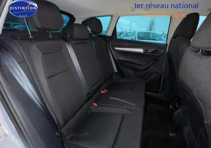 Vue intérieure côté gauche des sièges arrière noirs du Skoda Karoq 2025 blanc glacial avec appuie-têtes et ceintures visibles.