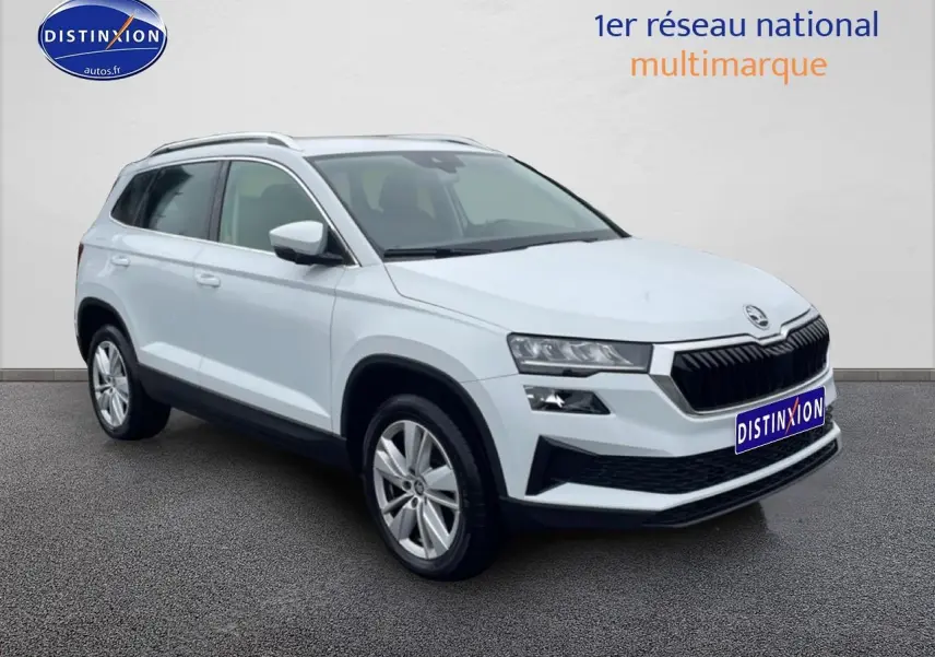 Vue 3/4 avant d'un Skoda Karoq blanc glacial avec calandre noire et jantes alu visibles.