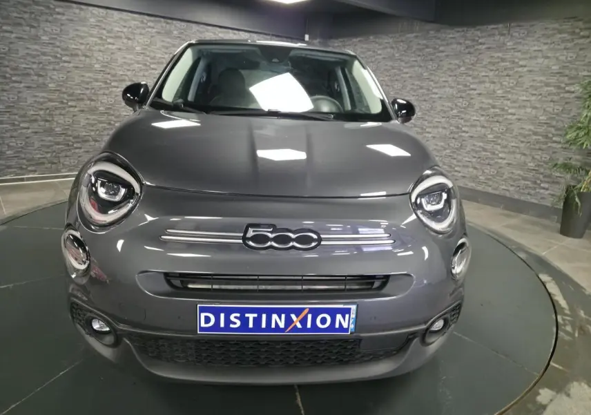 Vue avant d'une Fiat 500X gris métallisé avec phares LED et logo 500 bien visible sur fond intérieur gris.