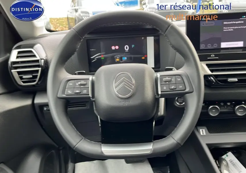 Vue centrée sur le volant cuir du Citroën C4 1.2 hybride 2025 avec tableau de bord numérique et écran tactile.