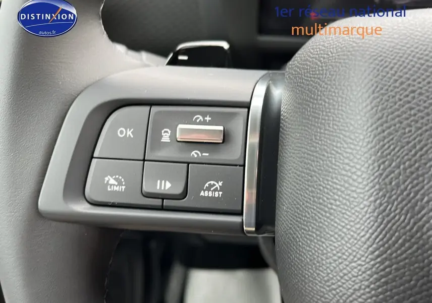 Gros plan sur les commandes de régulateur de vitesse au volant cuir d'une Citroën C4 noire métal 2025.