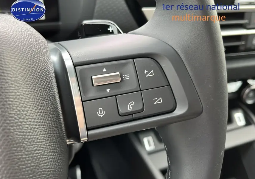 Gros plan sur les commandes vocales et téléphone du volant cuir d'une Citroën C4 hybride noire 2025.