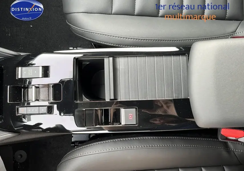 Vue plongeante sur la console centrale noire brillante de la Citroën C4 hybride 2025 avec commandes de boîte automatique et accoudoir cuir.