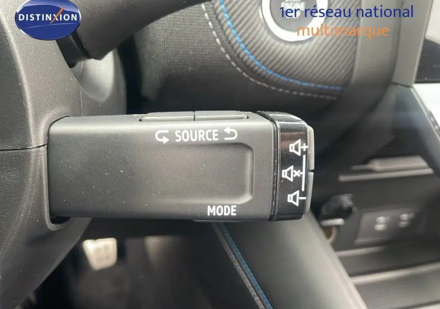 Gros plan sur la commande au volant du Renault Captur E-Tech hybride 2025, avec surpiqûres bleues et finition noire.