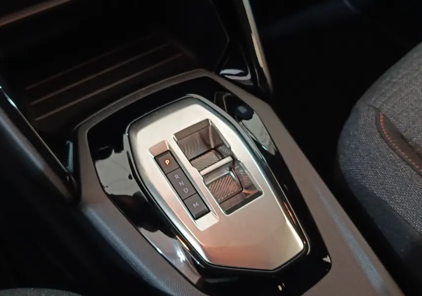 Gros plan sur la console centrale noire et argentée avec levier de vitesses automatique de la Peugeot 208 Hybrid 2025.