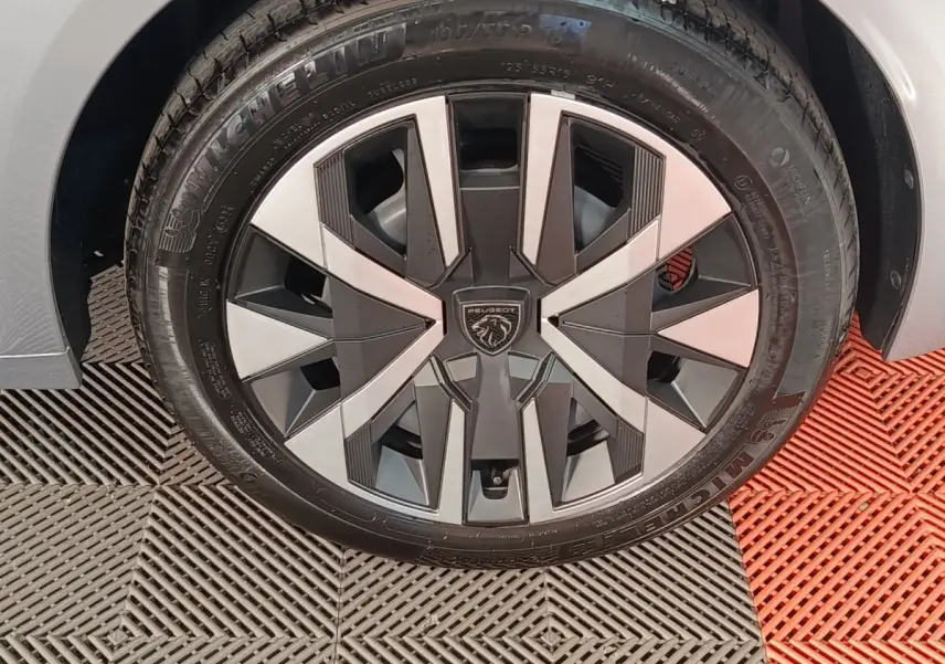Gros plan sur la roue avant droite de la Peugeot 208 Hybrid 100 e-DCS6 Style gris clair avec jante alliage au design moderne.