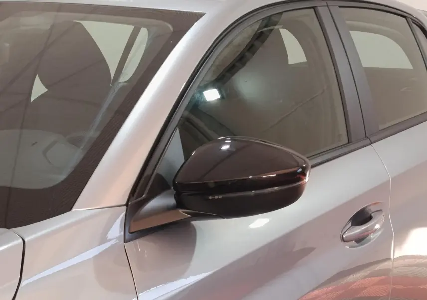 Gros plan sur le rétroviseur noir et la porte avant gauche d'une Peugeot 208 Hybrid gris clair, vue latérale.