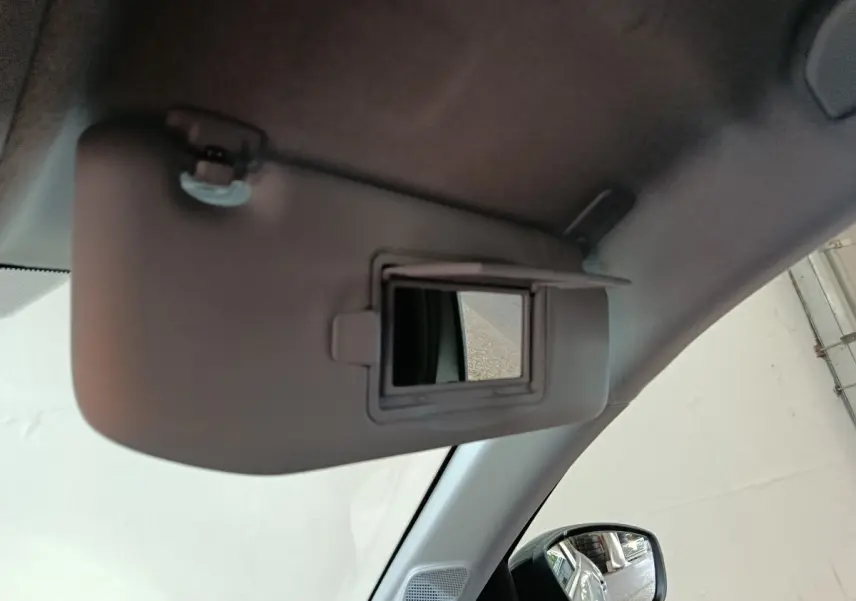 Détail intérieur montrant le pare-soleil avec miroir éclairant dans une Peugeot 208 Hybrid gris clair, côté conducteur.