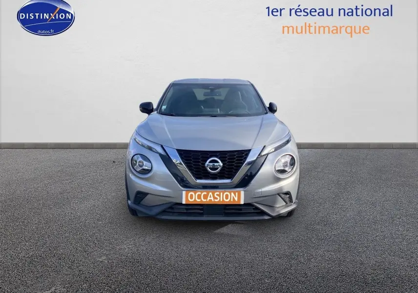 Vue de face d'un Nissan Juke gris clair 2021 avec calandre en V chromée et plaque "OCCASION" visible.