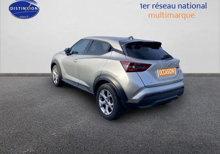 Nissan Juke gris clair vu en 3/4 arrière droit, avec jantes alliage et vitres teintées.