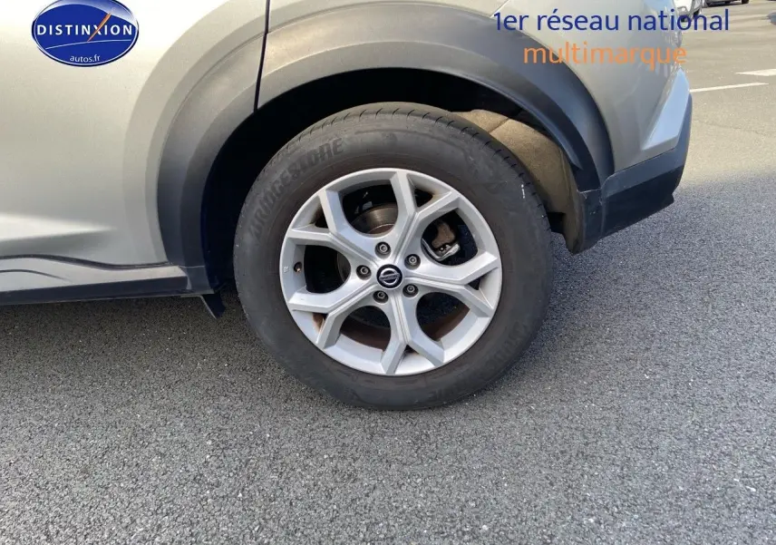 Gros plan sur la roue avant droite d'un Nissan Juke gris clair 2021 avec jante alliage à cinq branches.