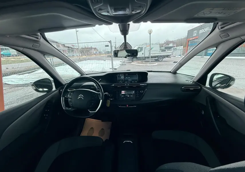 Vue intérieure avant du Citroën C4 Picasso gris platinium, montrant le tableau de bord et le volant multifonction.