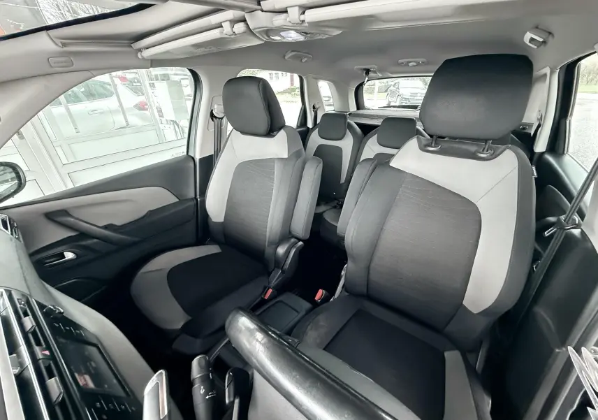 Vue intérieure avant de la Citroën C4 Picasso 2015, sièges tissu noir et gris, toit ouvrant panoramique visible.