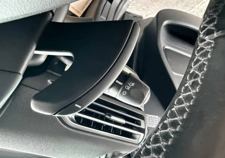 Détail du volant et commande d'éclairage côté gauche dans l'habitacle noir d'une Citroën C4 Picasso gris platinium.