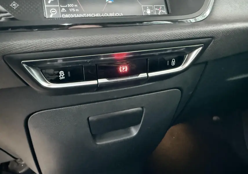 Détail du tableau de bord noir avec commandes électroniques et écran GPS visible dans une Citroën C4 Picasso 2015.
