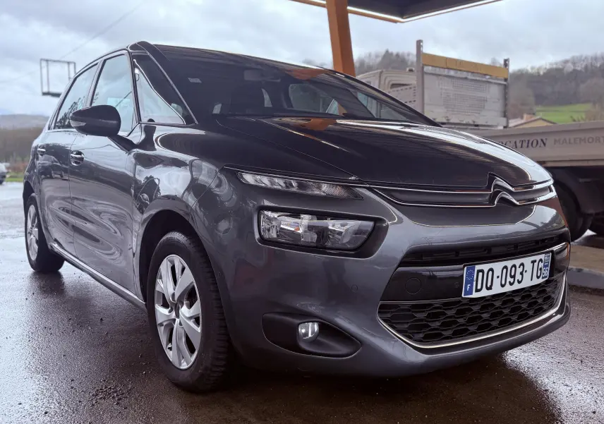 Citroën C4 Picasso gris platinium vue 3/4 avant droit sous abri avec calandre distinctive et phares LED.