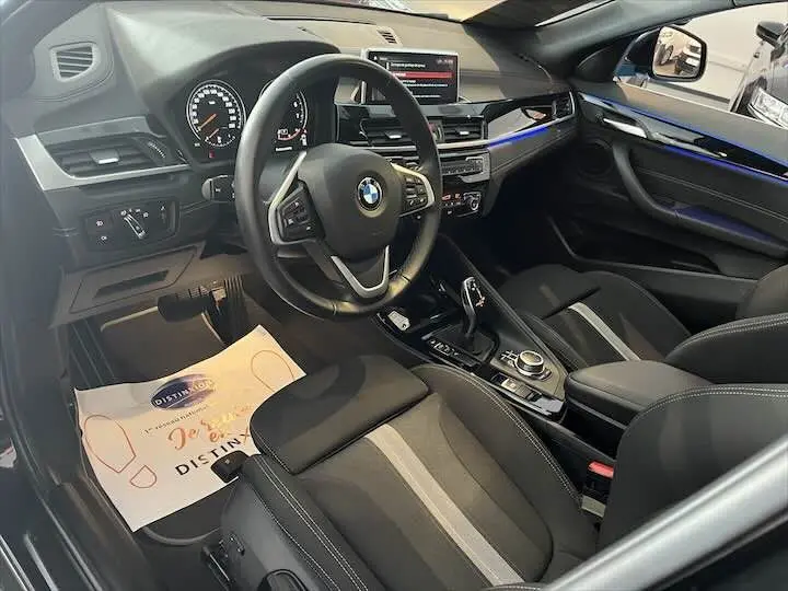 Intérieur noir de BMW X2 2022, vue côté conducteur montrant volant, tableau de bord et console centrale.