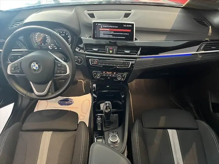 Vue intérieure avant du BMW X2 noir métal 2022, mettant en valeur le tableau de bord moderne et la console centrale avec écran tactile.