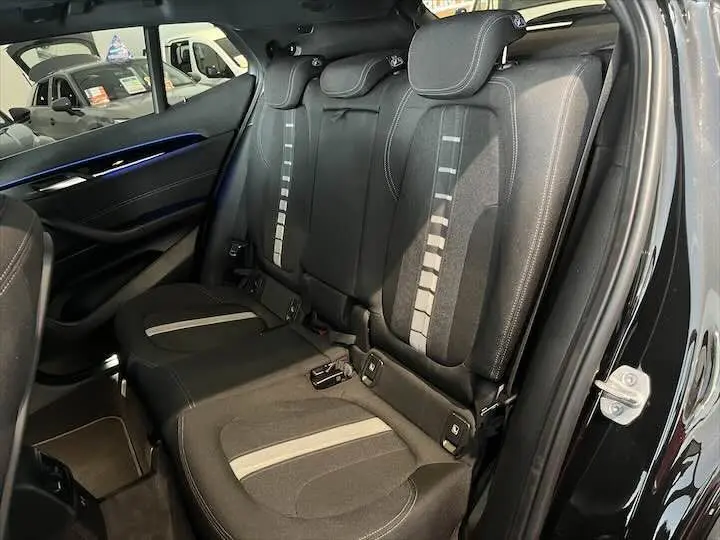Vue intérieure côté arrière droit des sièges noirs avec bandes grises du BMW X2 sDrive 18i 2022 toit ouvrant.