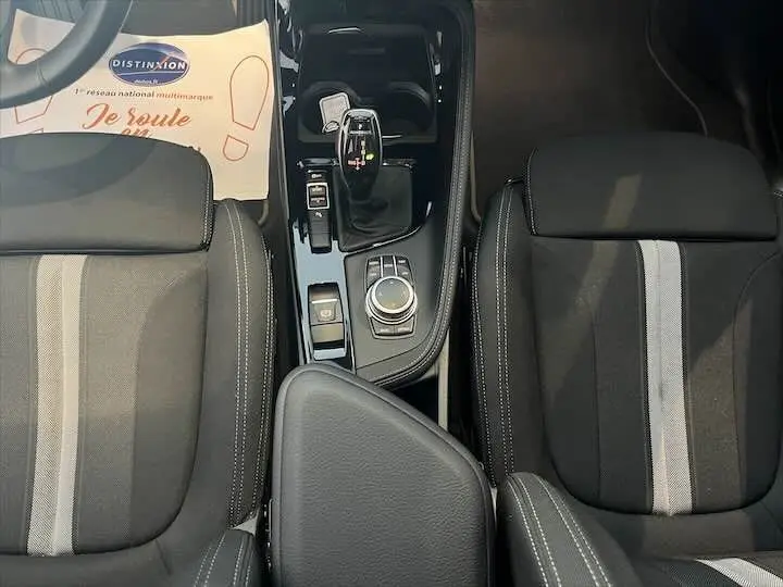 Vue plongeante sur la console centrale et les sièges noirs avec bandes grises du BMW X2 sDrive 18i 2022.