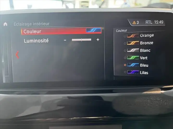 Écran central du BMW X2 noir métal 2021 montrant le menu de réglage de la couleur d'éclairage intérieur, option bleu sélectionnée.