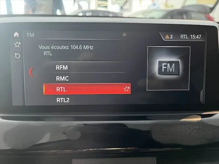 Écran central du BMW X2 noir métal 2022 affichant la sélection radio FM sur la station RTL à 15h47.