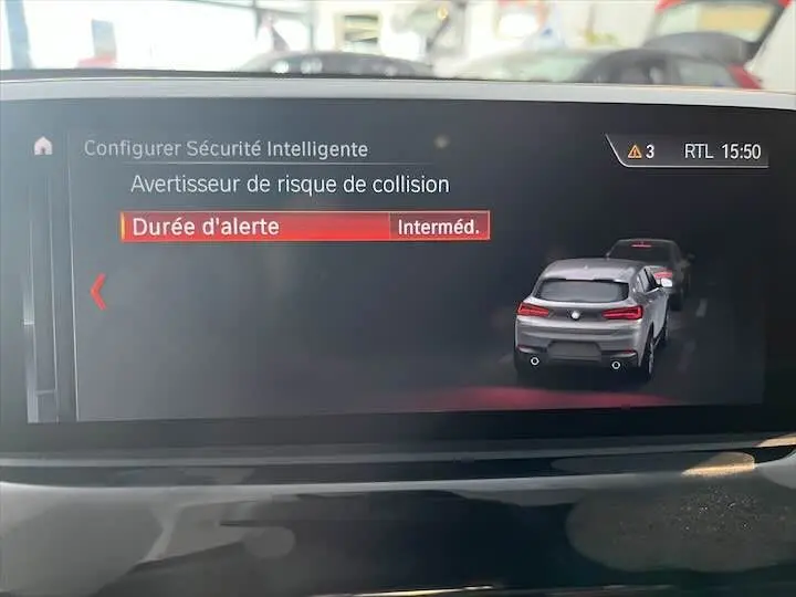 Écran de bord BMW X2 2022 montrant l'alerte de risque de collision avec véhicule noir métal vu de l'arrière