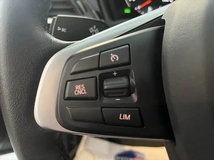 Gros plan sur les commandes de régulateur de vitesse au volant d’un BMW X2 noir métal modèle 2022.