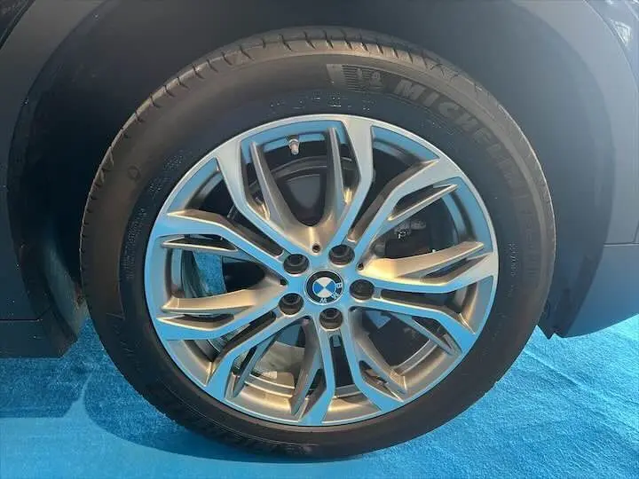 Gros plan sur la roue avant droite d'une BMW X2 noir métal, mettant en valeur la jante alliage et le pneu Michelin.