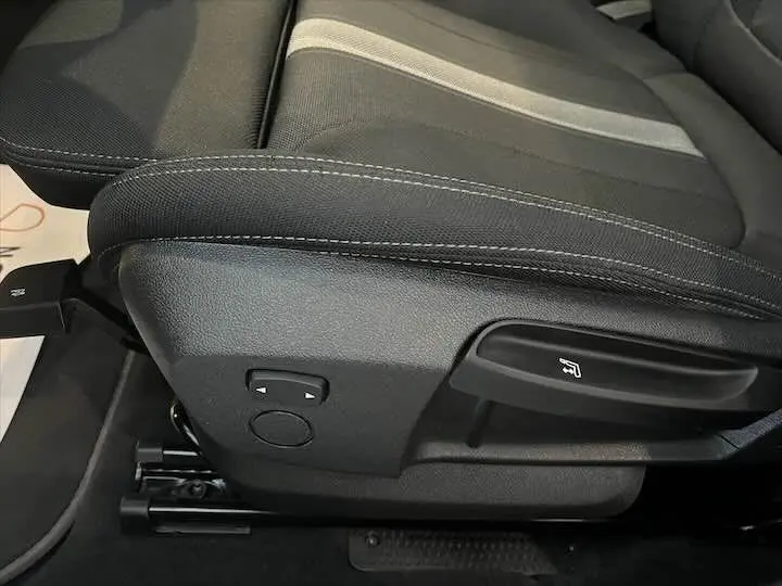 Gros plan sur le siège avant gauche noir du BMW X2 sDrive 18i 2021, montrant les commandes de réglage électrique.