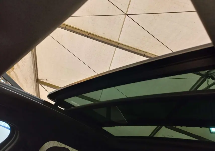 Toit ouvrant panoramique ouvert vu de l'intérieur sur BMW X2 noir métal, sous une tente blanche.