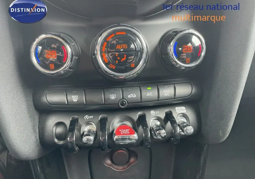 Gros plan sur la console centrale de la MINI 1.5 136CH STEPTRONIC 2023 avec commandes de climatisation et bouton start/stop rouge.