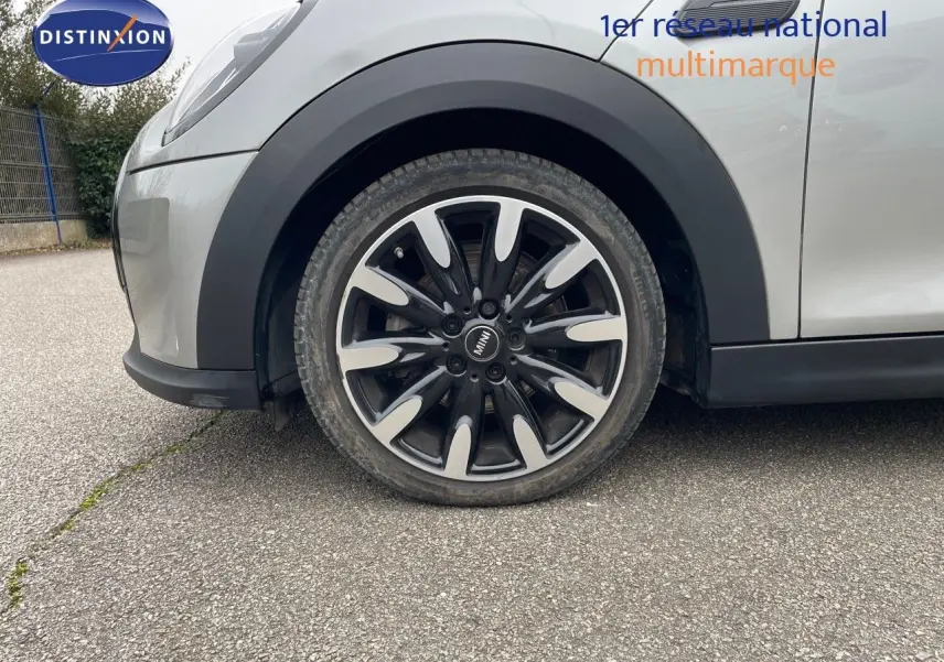 Gros plan sur la roue avant gauche d'une MINI 1.5 136CH STEPTRONIC 2023 couleur Melting Silver Metal avec jante bi-ton noire et argent.