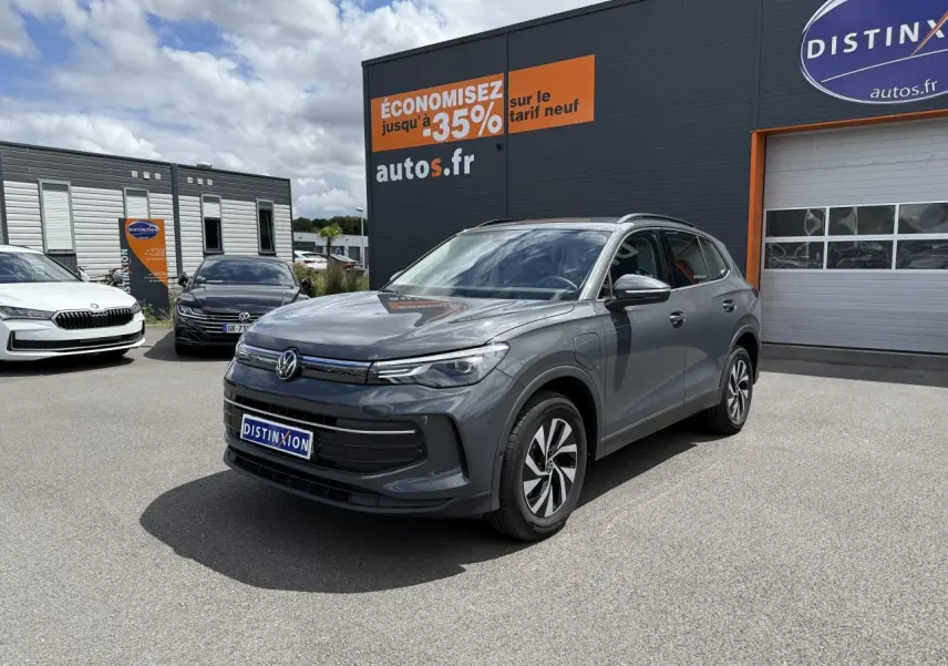Volkswagen Tiguan 1.5 eHybrid gris dauphin vu en 3/4 avant sur parking devant concession Distinxion.