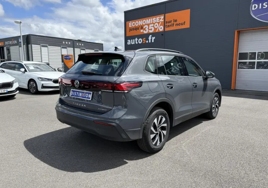 Vue 3/4 arrière droite d'un Volkswagen Tiguan gris dauphin hybride rechargeable avec jantes alliage et badge eHybrid.